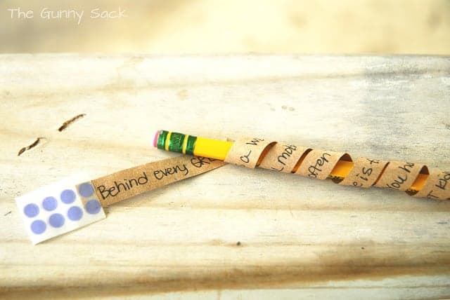 A strip of paper with words on it wrapped around a pencil.