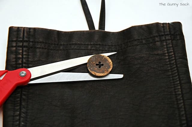 a button and scissors on top of a leather case.