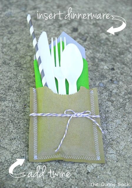a handmade paper pouch with plastic cutlery and napkins inside.