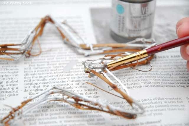  a paintbrush adding silver paint to an ornament.