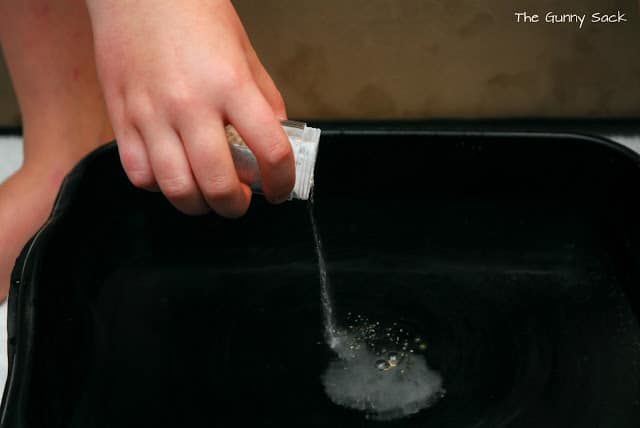 a hand pours powder into a foot bath.