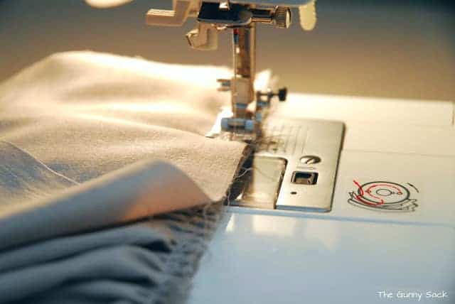 A sewing machine adding a row of stitching to ruffled fabric.