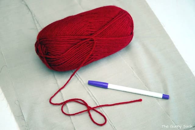 A ball of red yarn with a pen next to it.