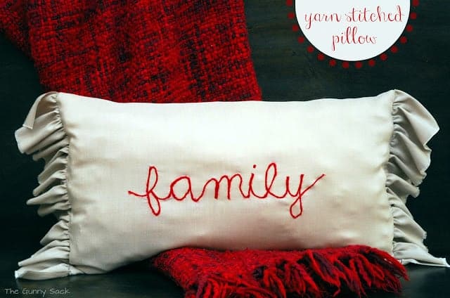 a white pillow with the word family stitched on it in red.