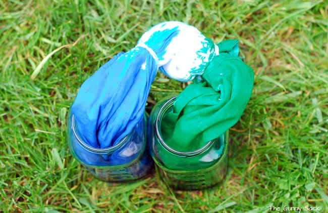 a cloth bag dipped into to separate jars of clothing dye.