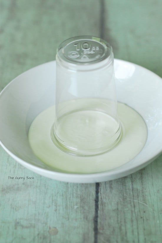 A plastic cup dipped in a bowl of melted candy.